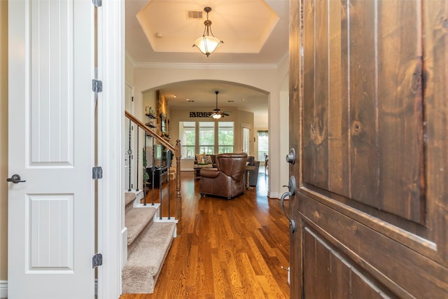 entrance foyer featuring ceiling fan, a raised ceiling, hardwood / wood-style floors, and crown molding