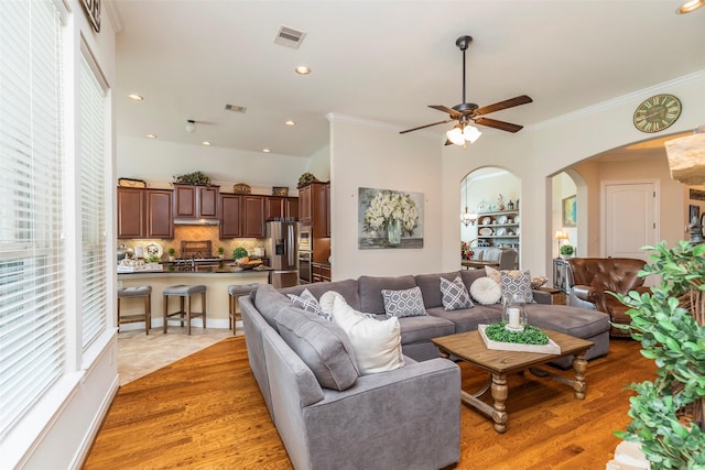 living room with ceiling fan, ornamental molding, and wood-type flooring