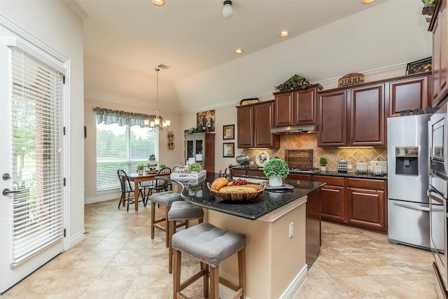 kitchen with appliances with stainless steel finishes, tasteful backsplash, a kitchen bar, a center island, and lofted ceiling