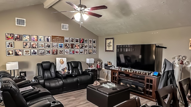 cinema room featuring ceiling fan, light wood-type flooring, and vaulted ceiling with beams