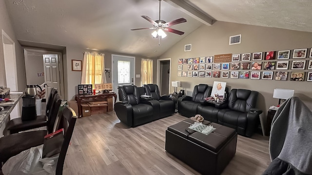 living room featuring a textured ceiling, ceiling fan, vaulted ceiling with beams, and hardwood / wood-style flooring