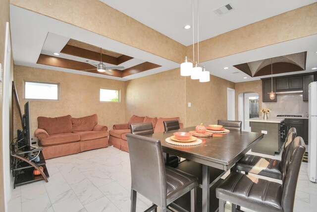 dining space with a raised ceiling and ceiling fan