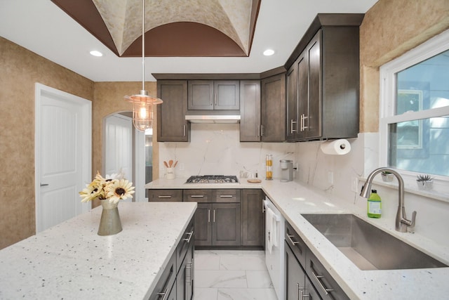 kitchen featuring sink, decorative light fixtures, dark brown cabinets, stainless steel gas stovetop, and light stone countertops