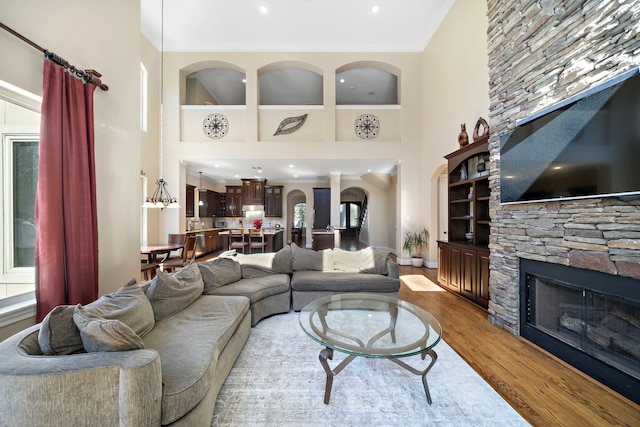 living room with a fireplace, a high ceiling, light wood-type flooring, and an inviting chandelier