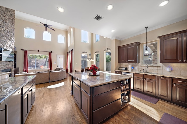 kitchen with tasteful backsplash, dark brown cabinets, sink, decorative light fixtures, and a center island