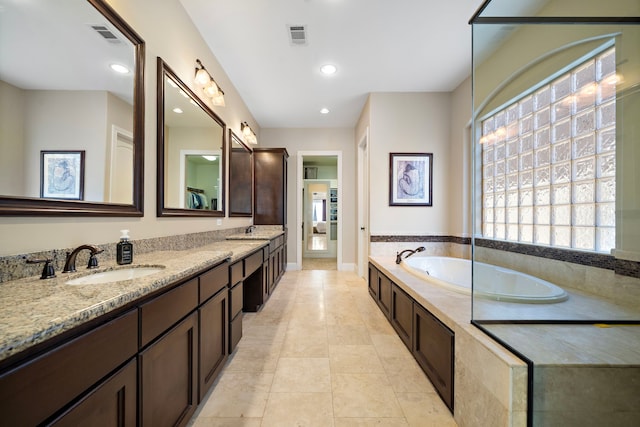 bathroom with tile patterned floors, vanity, and tiled bath