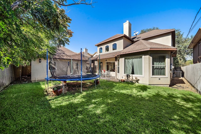 back of property featuring a lawn, cooling unit, a patio, and a trampoline