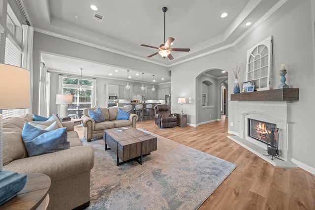 living room with ceiling fan, light hardwood / wood-style floors, and a raised ceiling