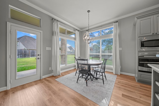 dining space featuring light hardwood / wood-style flooring, an inviting chandelier, and ornamental molding