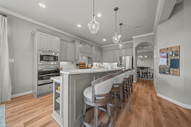 kitchen with gray cabinetry, an island with sink, appliances with stainless steel finishes, and tasteful backsplash