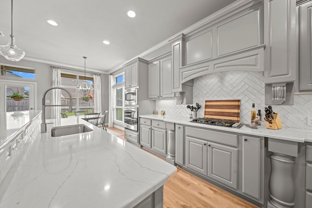 kitchen with gray cabinetry, decorative backsplash, sink, and hanging light fixtures