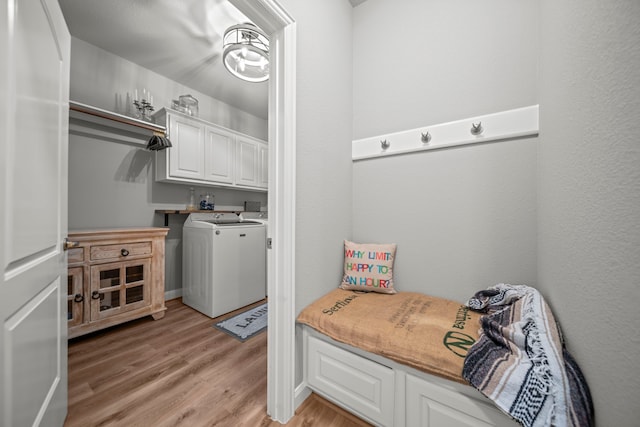 clothes washing area with light hardwood / wood-style floors, cabinets, and washing machine and clothes dryer