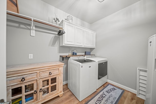 washroom featuring cabinets, washer and dryer, and light hardwood / wood-style floors