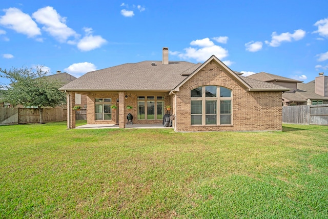 rear view of property featuring a lawn and a patio