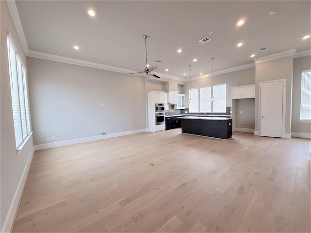 kitchen with white cabinetry, a center island, crown molding, and light hardwood / wood-style floors