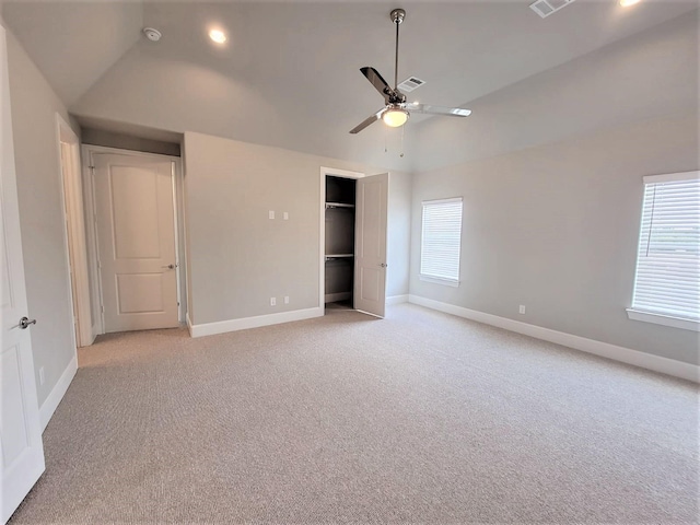 unfurnished bedroom with a closet, light colored carpet, vaulted ceiling, and ceiling fan