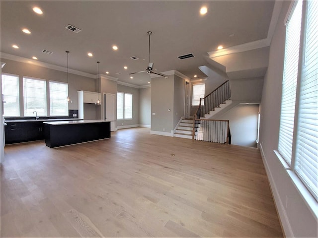 interior space with ceiling fan, a center island, light hardwood / wood-style floors, and decorative light fixtures