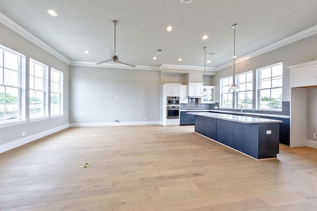 kitchen featuring white cabinets, ceiling fan, a center island, and tasteful backsplash