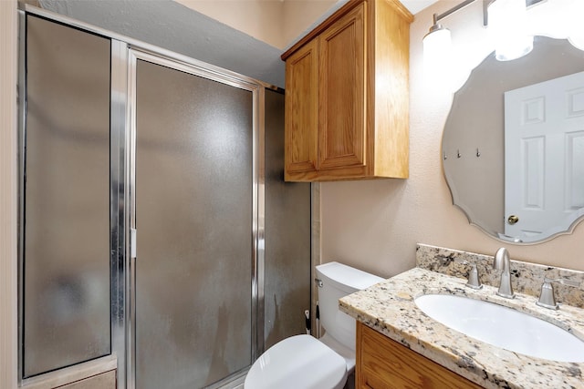 bathroom with vanity, toilet, and a shower with shower door