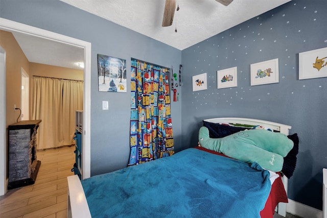 bedroom featuring a textured ceiling, light wood-type flooring, and ceiling fan