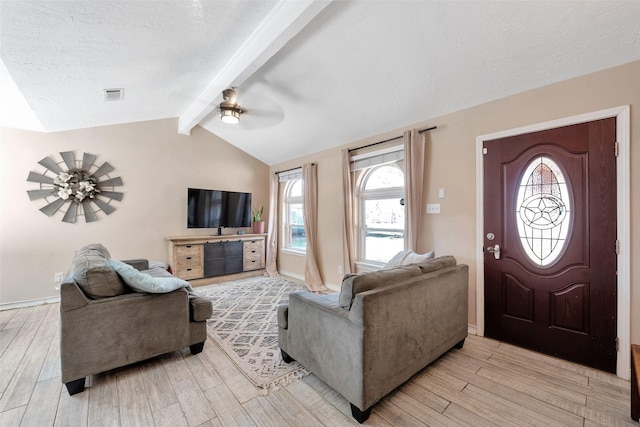 living room featuring vaulted ceiling with beams, ceiling fan, light hardwood / wood-style flooring, and a textured ceiling