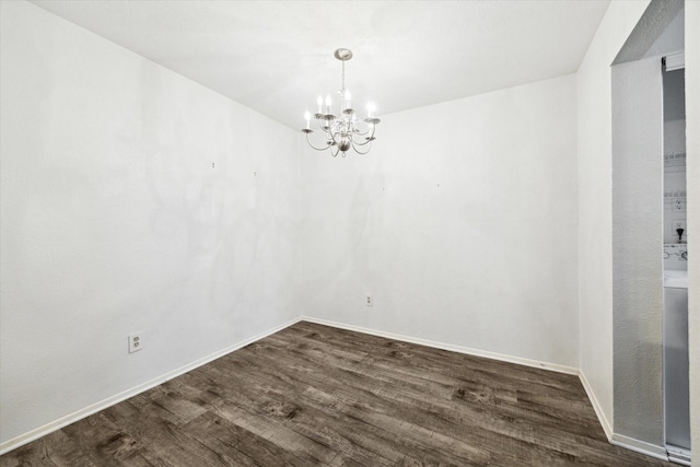 spare room with dark hardwood / wood-style floors and a notable chandelier