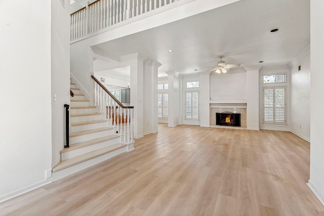 unfurnished living room featuring ornamental molding, light hardwood / wood-style flooring, ceiling fan, and a healthy amount of sunlight