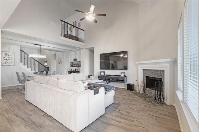 living room with a towering ceiling, light wood-type flooring, and ceiling fan