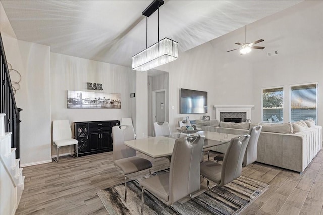 dining room featuring ceiling fan with notable chandelier and light hardwood / wood-style flooring