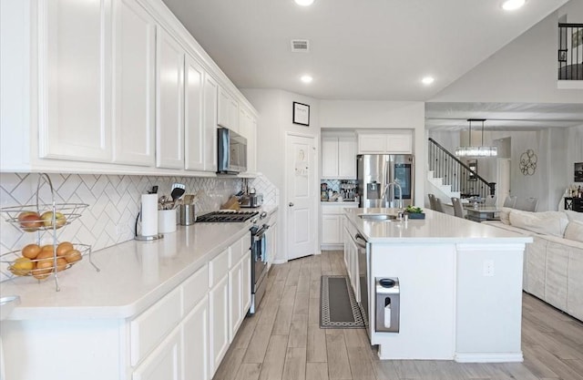 kitchen with white cabinets, a kitchen island with sink, appliances with stainless steel finishes, and sink