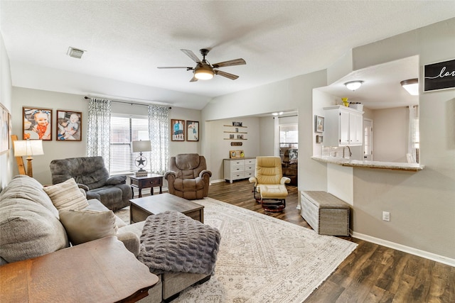 living room featuring ceiling fan, a textured ceiling, and dark hardwood / wood-style flooring