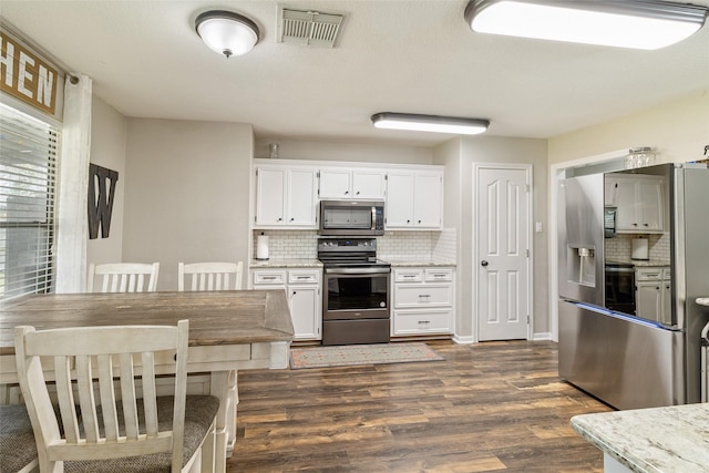 kitchen with stainless steel appliances, dark hardwood / wood-style flooring, white cabinets, and tasteful backsplash