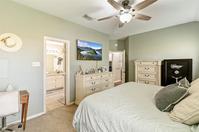 bedroom featuring ceiling fan, ensuite bath, light carpet, and vaulted ceiling