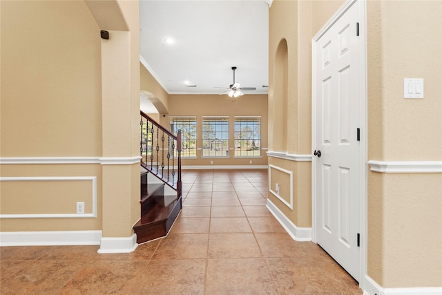 foyer featuring ceiling fan, light tile patterned flooring, and ornamental molding