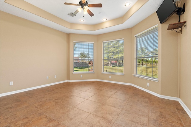 spare room with a tray ceiling, ceiling fan, and light tile patterned floors