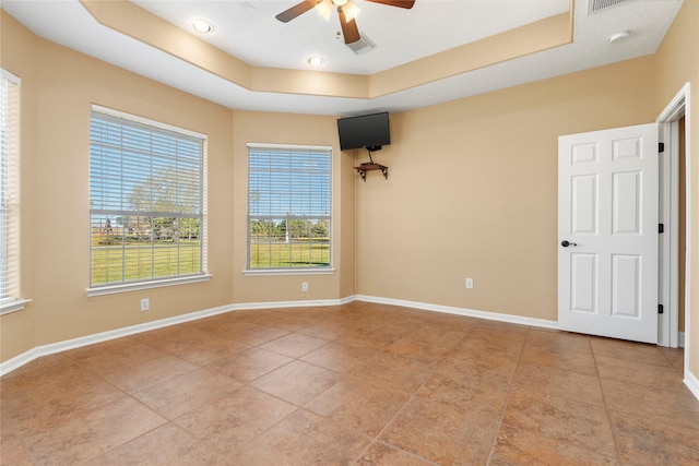 spare room with ceiling fan, light tile patterned flooring, and a raised ceiling