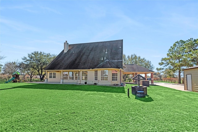 back of house with a playground and a yard