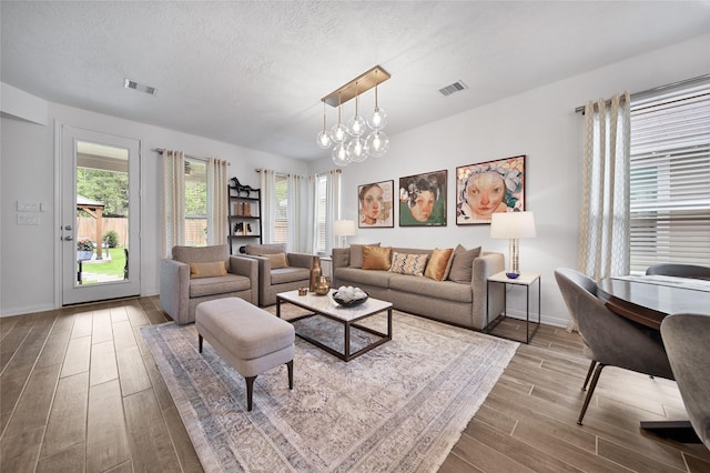 living room with a textured ceiling, a chandelier, and light wood-type flooring