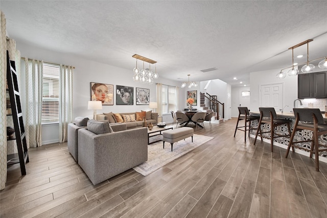 living room with wood-type flooring, an inviting chandelier, and a textured ceiling