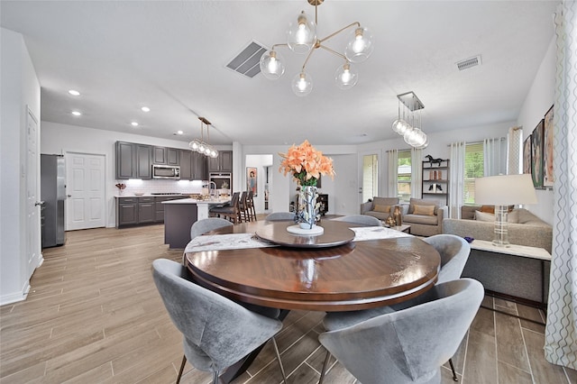 dining area with an inviting chandelier and light hardwood / wood-style floors