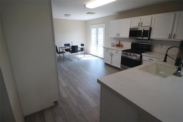 kitchen featuring white cabinets, sink, decorative backsplash, light stone counters, and stainless steel appliances