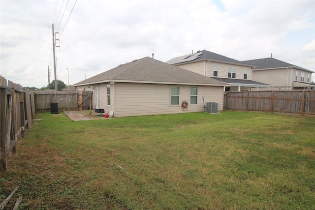 rear view of property featuring central AC and a yard