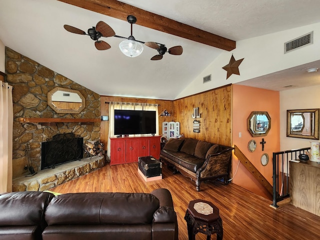 living room featuring a stone fireplace, wooden walls, vaulted ceiling with beams, ceiling fan, and wood-type flooring