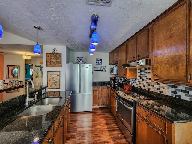 kitchen featuring appliances with stainless steel finishes, dark stone counters, sink, pendant lighting, and dark hardwood / wood-style floors