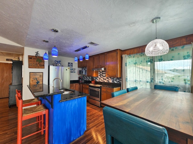 kitchen featuring a breakfast bar area, sink, pendant lighting, and appliances with stainless steel finishes