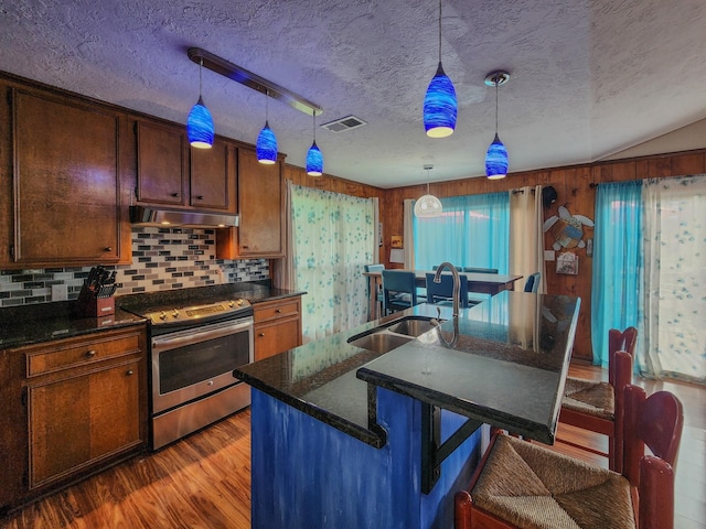 kitchen with sink, hanging light fixtures, a textured ceiling, stainless steel range oven, and a breakfast bar area