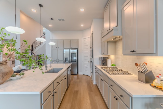 kitchen with pendant lighting, gray cabinetry, sink, appliances with stainless steel finishes, and tasteful backsplash