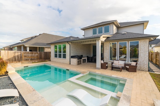 back of house with an outdoor living space, a patio, an outdoor kitchen, and a pool with hot tub