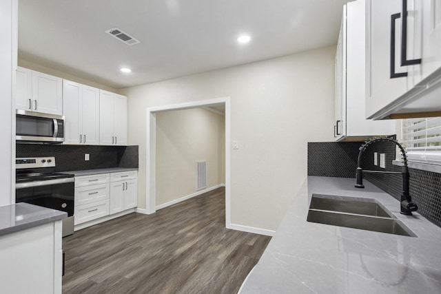 kitchen featuring white cabinetry, sink, dark wood-type flooring, stainless steel appliances, and tasteful backsplash