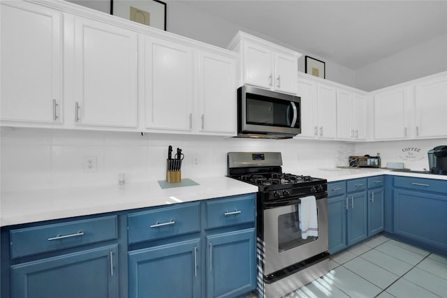 kitchen with white cabinetry, stainless steel appliances, blue cabinets, backsplash, and light tile patterned floors